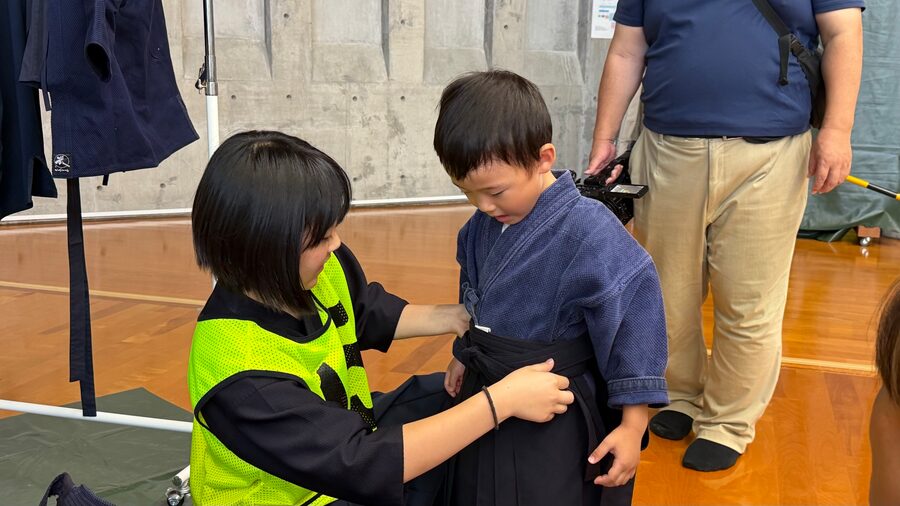 スタッフに袴を着せてもらう子ども