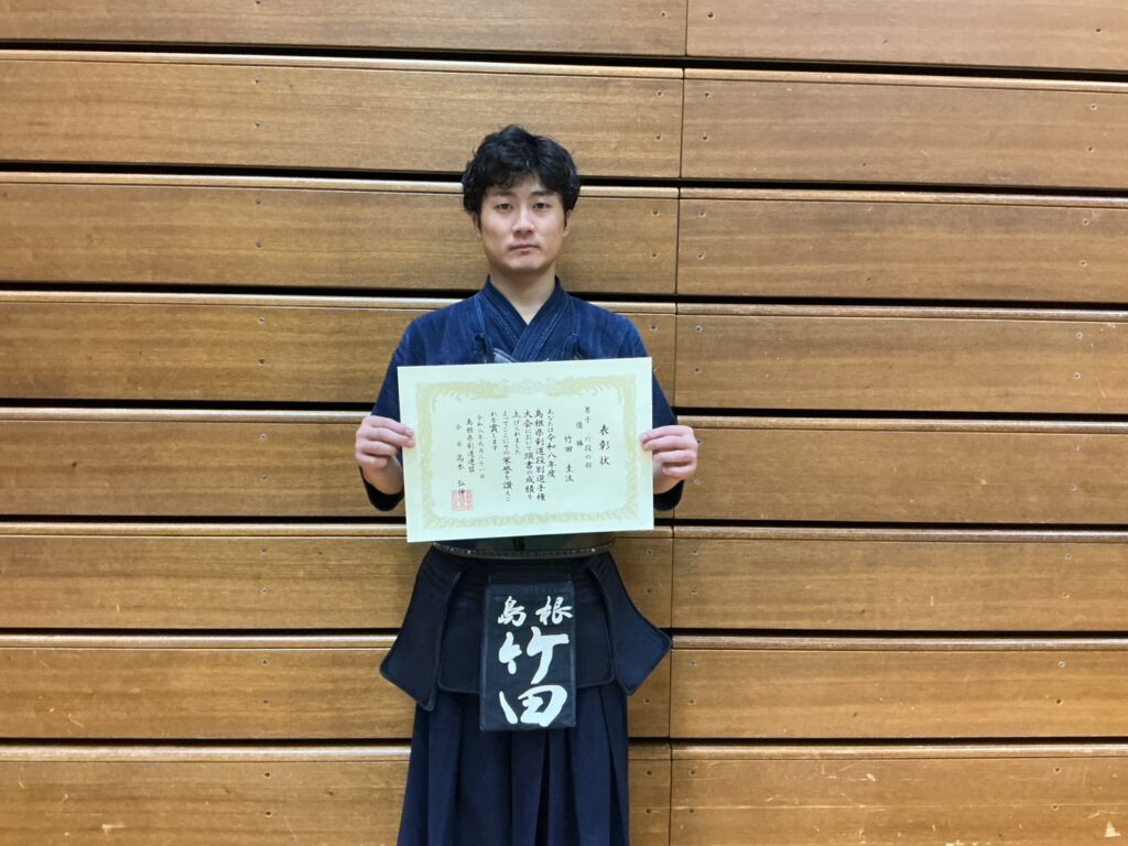 男子六段の部の優勝者が賞状を持つ