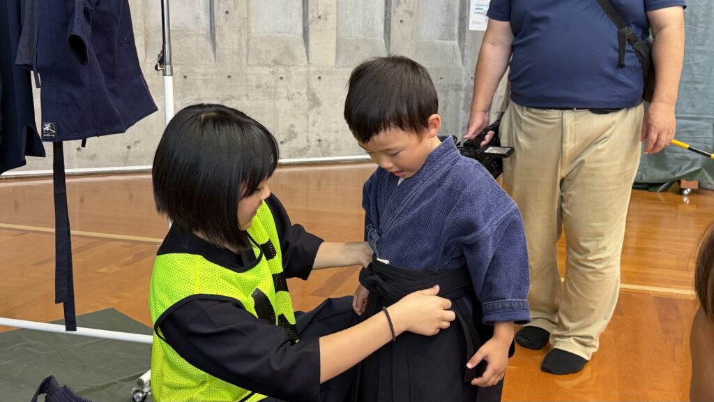 スタッフに袴を着せてもらう子ども